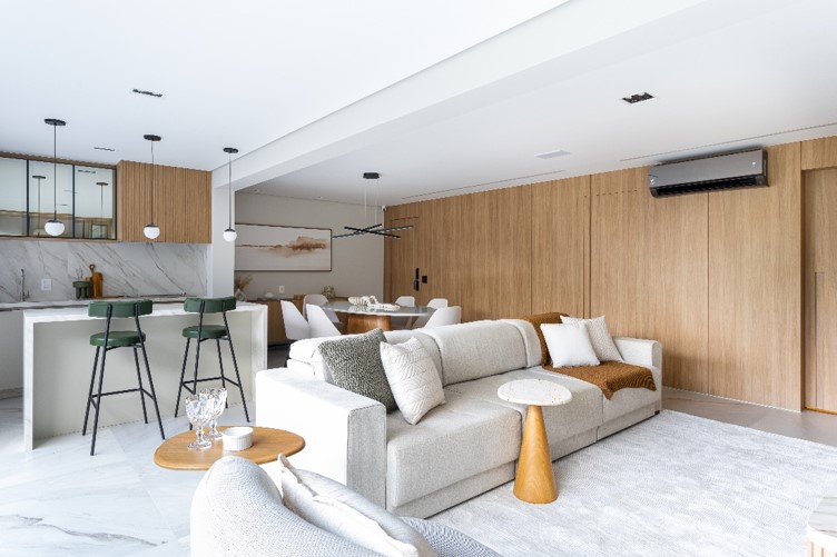 A utilização da madeira Freijó, presente no revestimento das paredes com suas portas ocultadas, entrega a linguagem uníssona que a arquiteta Mari Milani estabeleceu na área social do apartamento | Foto: Bianca Versolato
